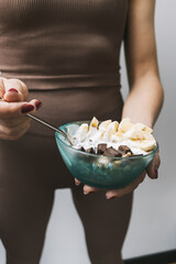 Athletic woman in sportswear eating healthy food for breakfast, cereal, granola, muesli, oatmeal...