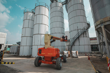 Obraz premium Male industry working at high in a boom liftinspection tank silo