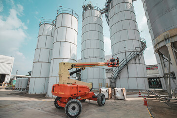 Male industry working at high in a boom liftinspection tank silo