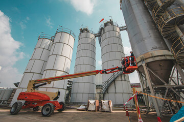 Male industry working at high in a boom liftinspection tank silo
