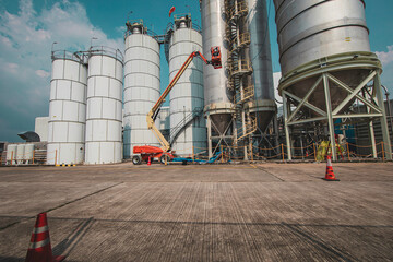 Male industry working at high in a boom liftinspection tank silo