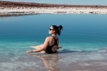 Woman enjoys floating on salt saturated water in Laguna Baltinache, Atacama. Chile