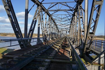 a railroad track crosses an old steel bridge across a waterway