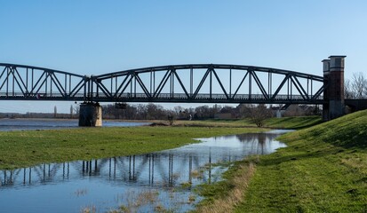 Obraz premium Majestic bridge stretching over a calm body of water with green grassy shore