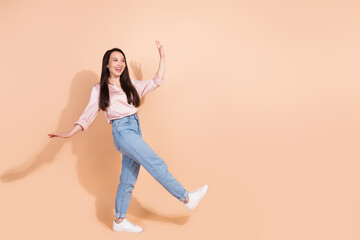 Fototapeta na wymiar Full length photo of pleasant asian girl wear pink shirt jeans pants dancing look at sale empty space isolated on pastel color background