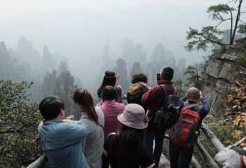 Group of tourists taking photos from a vantage point with mobile phones in Zhangjiajie National...
