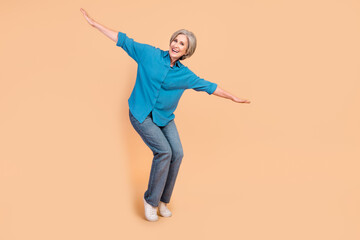 Full length photo of positive carefree retired person wear blue shirt jeans holding palms like wings isolated on beige color background