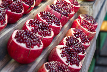 Fresh pomegranate cut in half on stall at shop. Ripe pomegranates closeup with selective focus.