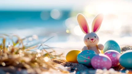 Fotobehang a plush bunny sits on a sandy beach surrounded by colorful Easter eggs © PETR BABKIN