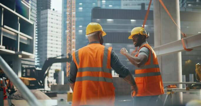 Two Diverse Construction Site General Operator's High Five While Walking to Work. Cinematic Footage From the Back with Two Successful Male Construction Workers Walking Away
