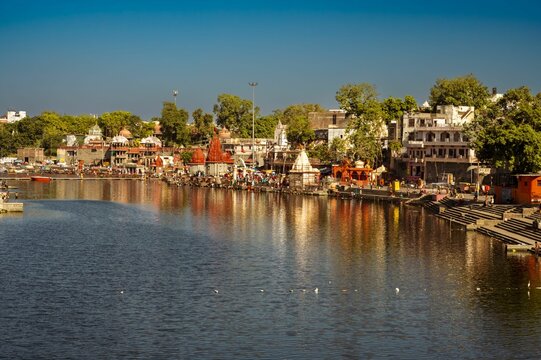 Scenic view of a tranquil river with various small boats and houses in Ujjain, Ram Ghat