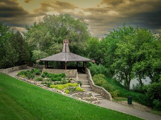 Outdoor gazebo situated in a lush green grassy field with a tranquil body of water in the background