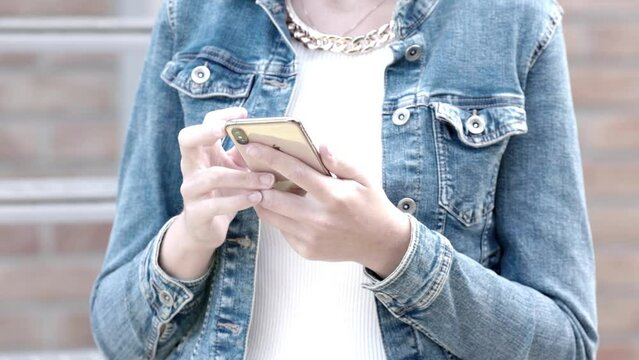 This stock footage thoughtfully depicts a moment of modern connectivity, featuring an individual in a denim jacket interacting with a smartphone in slow motion. The slowed pace allows viewers to