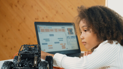 African girl writing car model structure while laptop display code. Smart student working by using...