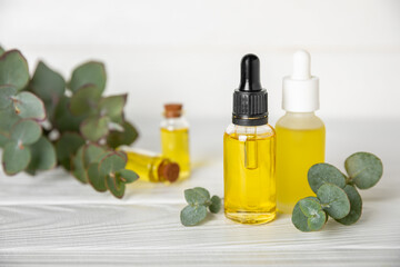 Eucalyptus essential oil in a glass bottle with green eucalyptus leaves on a textured wooden background. Aromatherapy concept. Spa. Natural organic ingredients for cosmetics and body care.Copy space