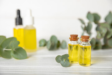 Eucalyptus essential oil in a glass bottle with green eucalyptus leaves on a textured wooden background. Aromatherapy concept. Spa. Natural organic ingredients for cosmetics and body care.Copy space
