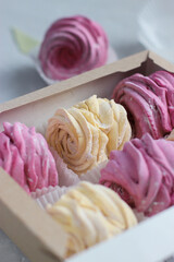 Gift box of handmade black currant and banana marshmallow (zephyr). Close up view of creamy pale yellow and violet zefir on the grey background. Traditional Russian dessert. Romantic present concept