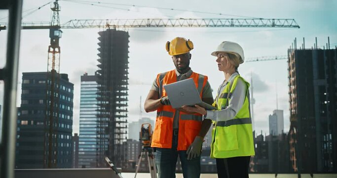 Site Manager Talking with African General Construction Operative at a Residential Building Construction Area. Female and Male Employees Using a Laptop Computer to Oversee Project Development Plan