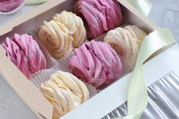Gift box full of black currant and banana marshmallow. Close up view of creamy pale yellow and violet zefir on the grey background. Traditional Russian dessert. Romantic idea for present. Business