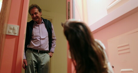 Little girl opening front door welcoming grand-father casual family moment