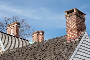 Three chimneys on the roof of these older homes.
