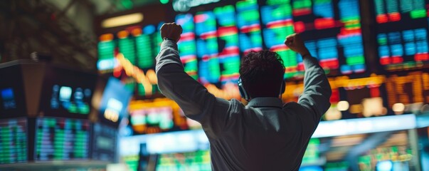 A man in business attire celebrates with raised hands on a trading floor, symbolizing financial victory amidst vibrant stock market boards.