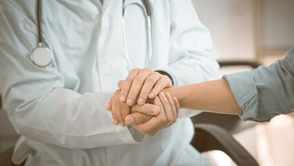 Support, trust and hospital care with a doctor and patient holding hands, sharing bad news of a...