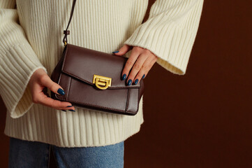 Close up photo of trendy brown  leather shoulder bag, purse in fashionable outfit. Woman wearing...