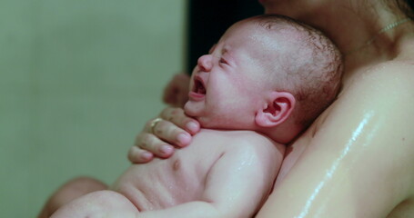 Mom bathing and showering crying baby infant son
