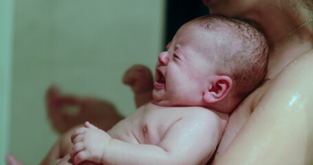 Mom bathing and showering crying baby infant son