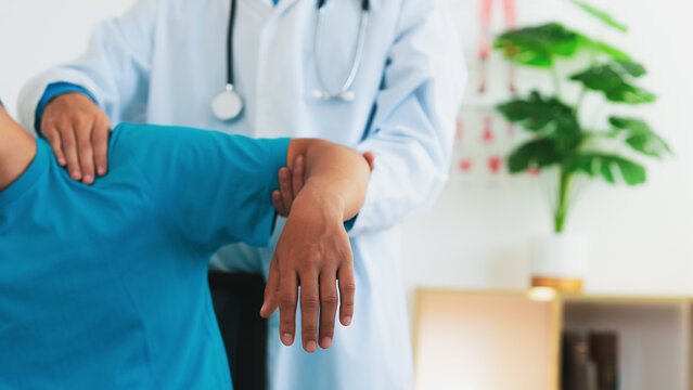 A physical therapist is treating a man with shoulder pain and suffering from frozen shoulder,pain and stiffness,unable to move,difficulty lifting his arm,male people with calcific tendonitis.