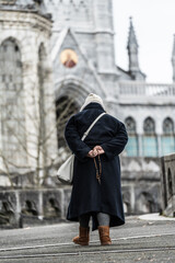 Fototapeta na wymiar An elderly woman in black walks to church to pray.