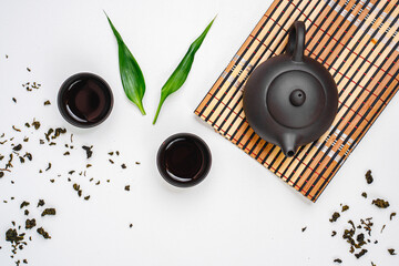 Black teapot and cups with bamboo leaves on a tray. Traditional tea ceremony. Green Tea Composition with bamboo leaves, banner. Chinese traditional tea set, tea ceremony concept, top view, copy space.