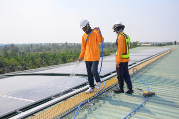 Professional worker cleans solar panels with brush and rinses with water on roof structure of...