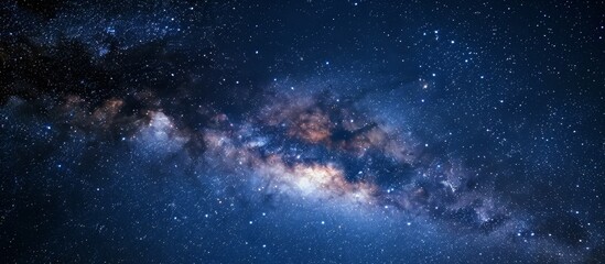 Naklejka premium The Milky Way galaxy, an astronomical object, is visible in the night sky filled with electric blue atmosphere and scattered clouds.