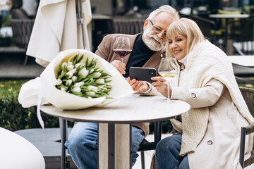 A romantic date of an elderly couple celebrating their anniversary in a cafe