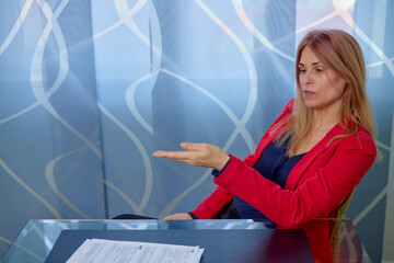 business woman in the office At a table with documents, she invites you to sign a contract.