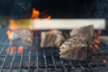 A close-up of burning barbecue coals and pieces of pork. Pieces of pork on the grill.	