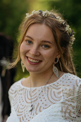 Radiant young woman with floral headband smiling in a natural setting.