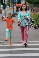 Mother and daughter crossing the street, enjoying a lively urban walk together.