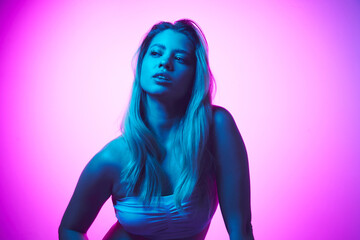 Gel portrait of beautiful, young, blonde woman with spotless, clear skin and nude makeup against gradient studio background in neon light. Concept of beauty, skincare, cosmetics and cosmetology