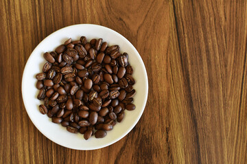Granos de café Guatemalteco tostado sobre un plato de porcelana blanco.