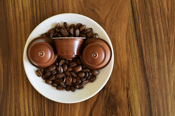 Granos y capsulas de café en un plato de porcelana blanco.