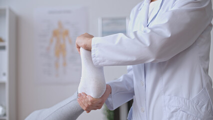 A traumatologist facilitates a patient's foot exercise, focusing on rehabilitation after a sports...