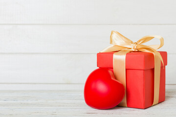 gift box with red bow and red heart on colored background. Perspective view. Flat lay