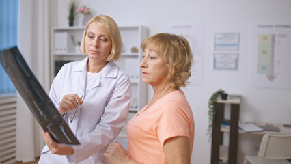 A concentrated traumatologist and a senior patient examine an X-ray image, discussing the diagnosis