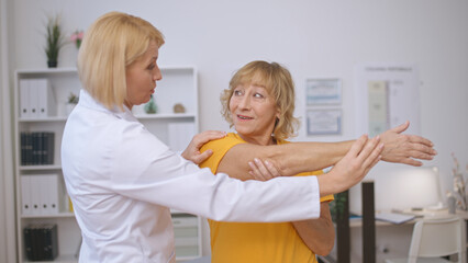 A senior patient and a rehabilitation doctor perform a stretching exercise together