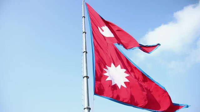Nepal national flag. Nepal flag waving in the blue sky. Nepal Flag Flying High With Pride.
