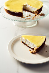 Mascarpone cheesecake with lemon curd and shortbread base. White marble background. High key food photo