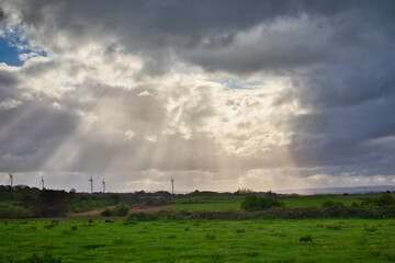 Sunbeams breaking through the clouds and shining on a green landscape